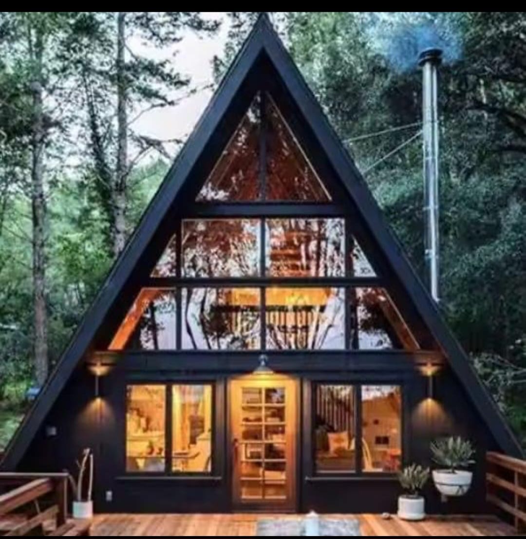 Finnhäuser – Klassisches schwarzes A-Frame im Wald · warme Innenbeleuchtung · Ofenrohr